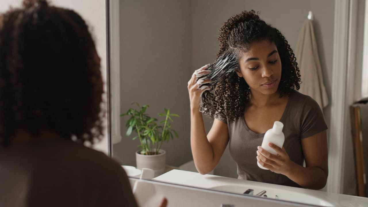 Conditioner applied from mid-lengths down on curly hair, scalp left clear